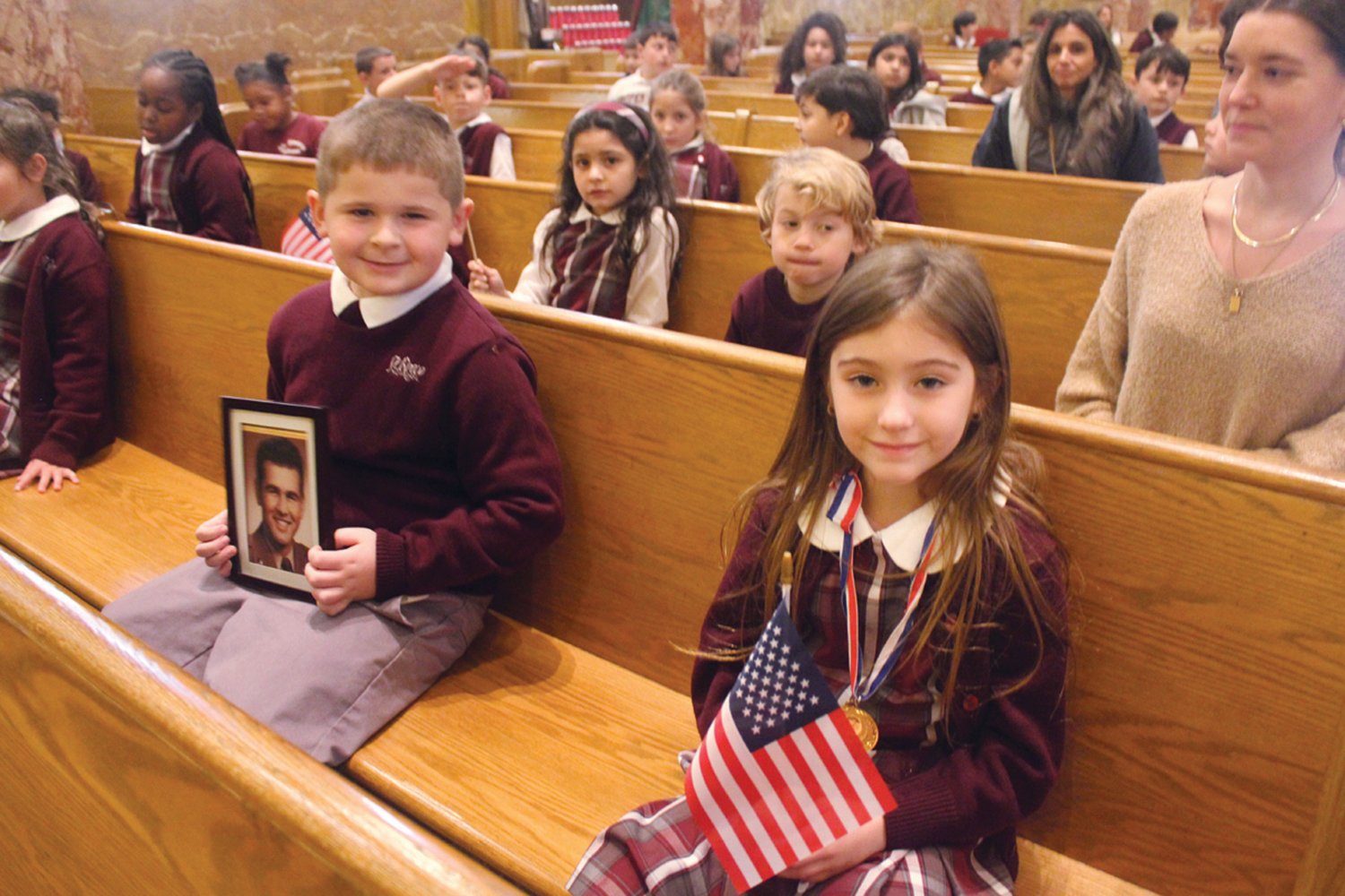 PRAYERS FOR OUR PROTECTORS: First grade students Mila Paolucci and Nicholas Innocenti attended St. Rocco School’s Veterans Day Prayer Service on Wednesday, Nov. 9. Innocenti held a photo of his great-grandfather, a veteran.
